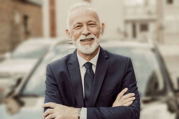 Elderly business man smiling  in front a car